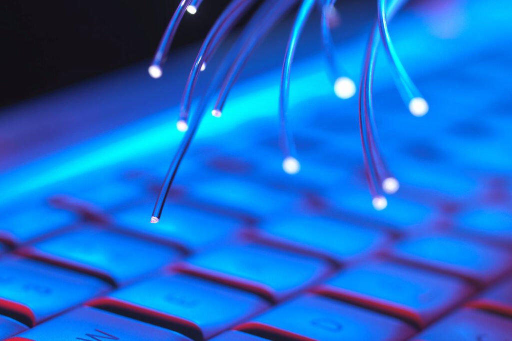 Illuminated keyboard with glowing fiber optic cables, representing digital infrastructure