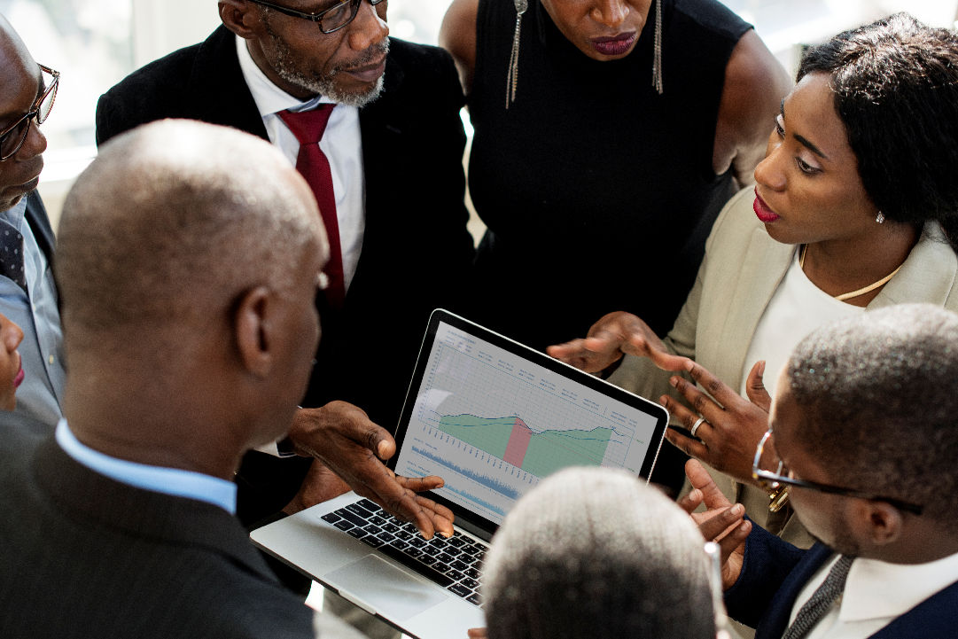 Business team analyzing financial performance trends on a laptop with multi-line chart and shaded areas, representing monthly data insights.